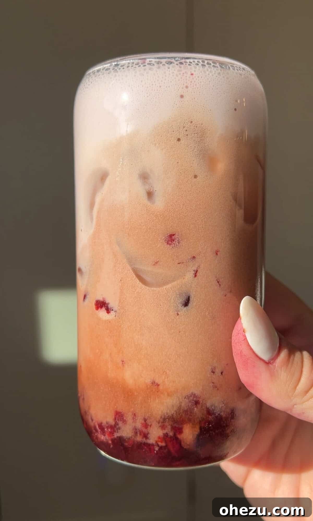 a hand holding a glass of cherry pie dr pepper