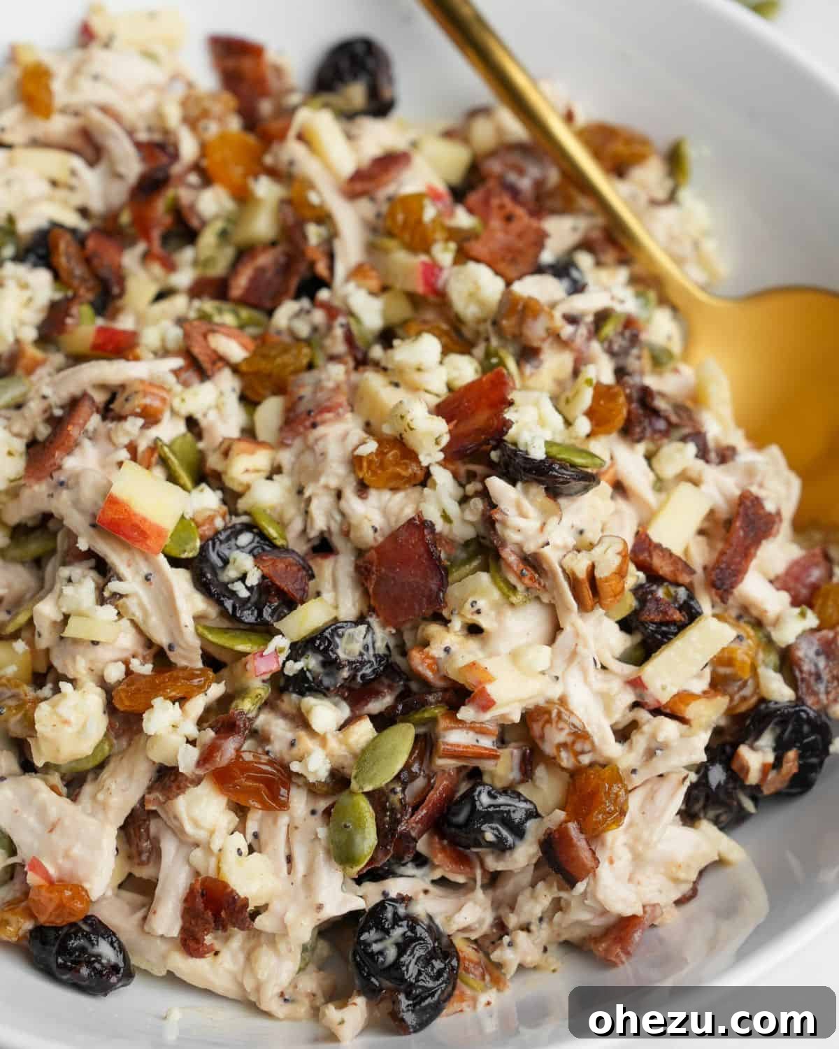 This autumn-inspired chicken salad with apples is an ideal blend of savory chicken, crisp apples, crunchy pecans, and so much more. Autumn chicken salad with apples, pecans, and dried cherries in a rustic white bowl.
