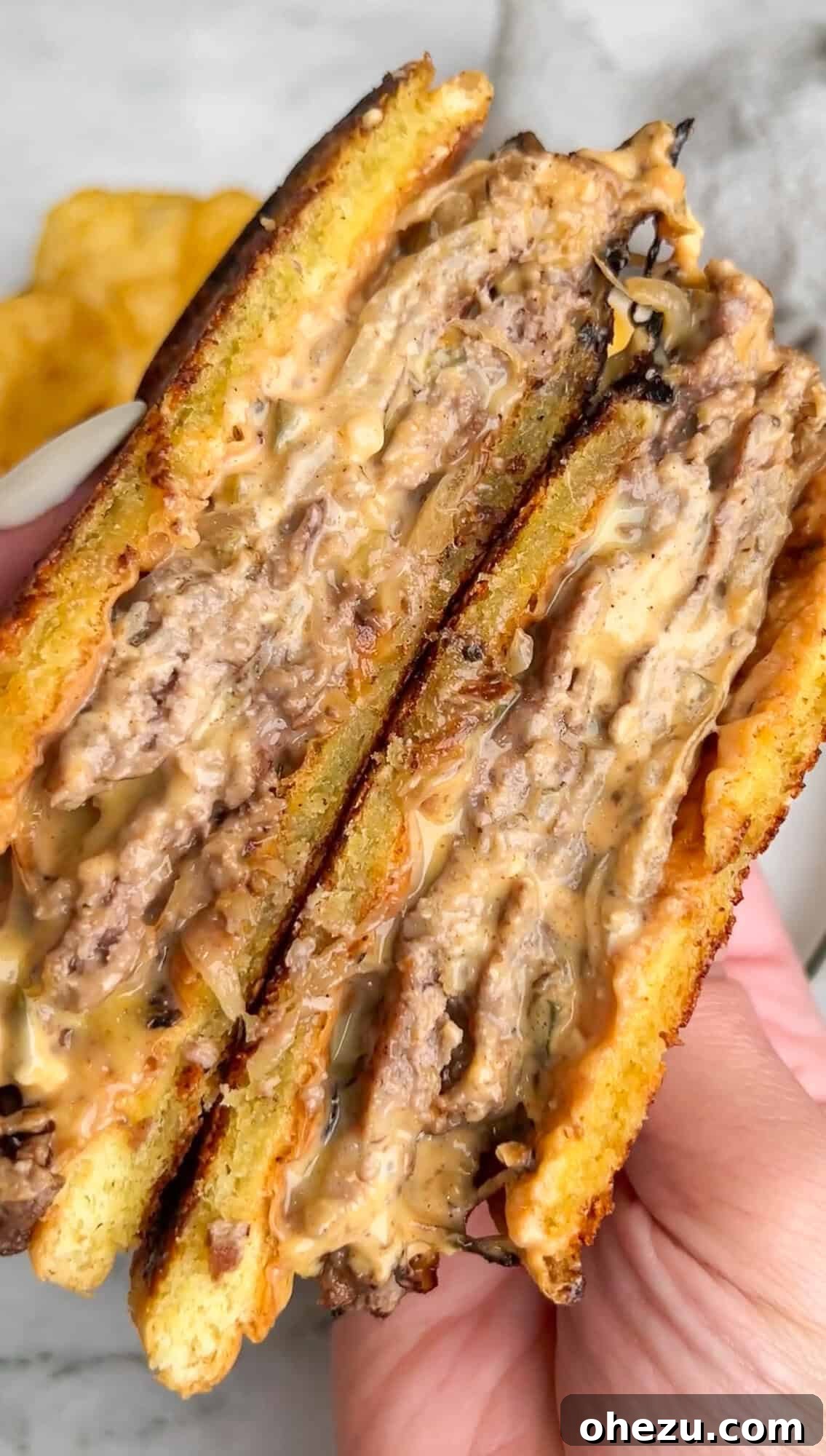 Smashburger Grilled Cheese sliced in half to reveal layers of patty, melted cheese, and sauce