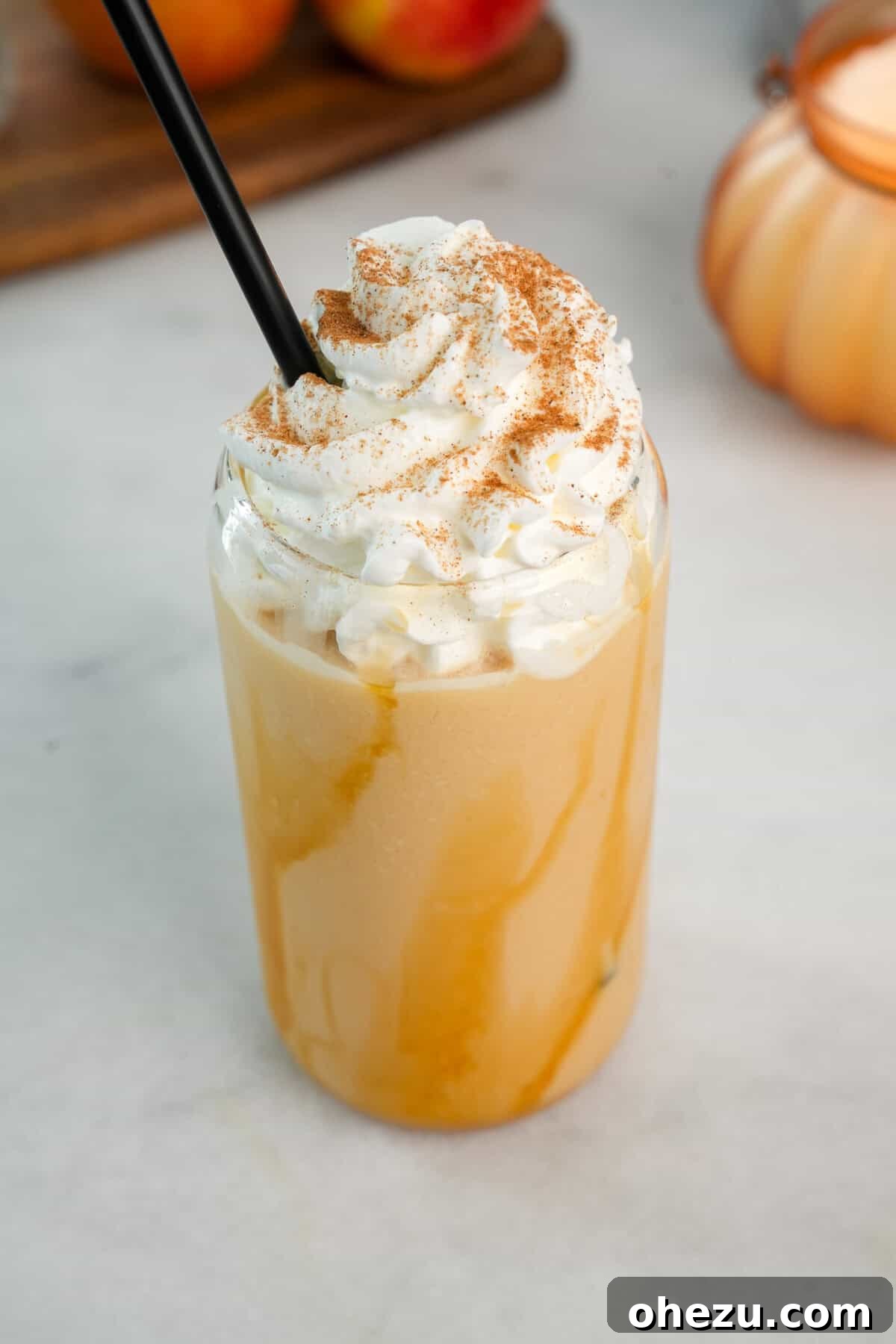 A beautifully garnished, creamy fall beverage: Whipped Apple Cider with a swirl of whipped cream and caramel drizzle.