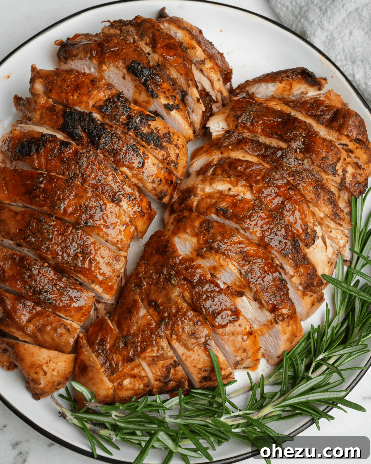 Bayou Blast Turkey 2 sliced turkey breasts on a plate with rosemary