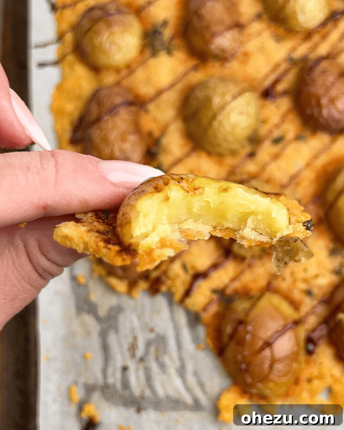 A single Parmesan roasted potato with a bite taken, revealing its soft, creamy interior contrasting with the crispy exterior.