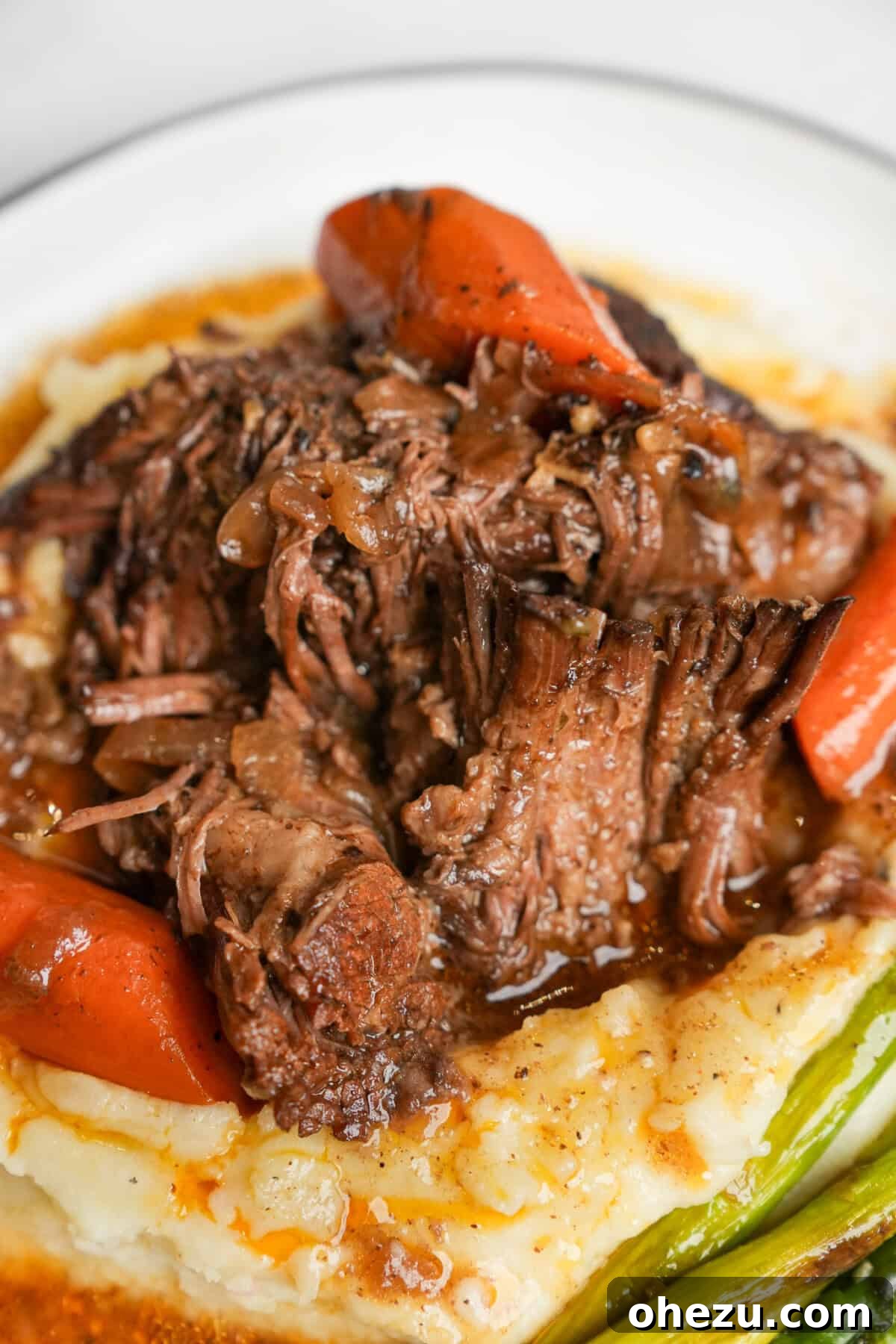 Close-up of Mississippi pot roast served on mashed potatoes, clearly showing the beautifully caramelized exterior of the meat.