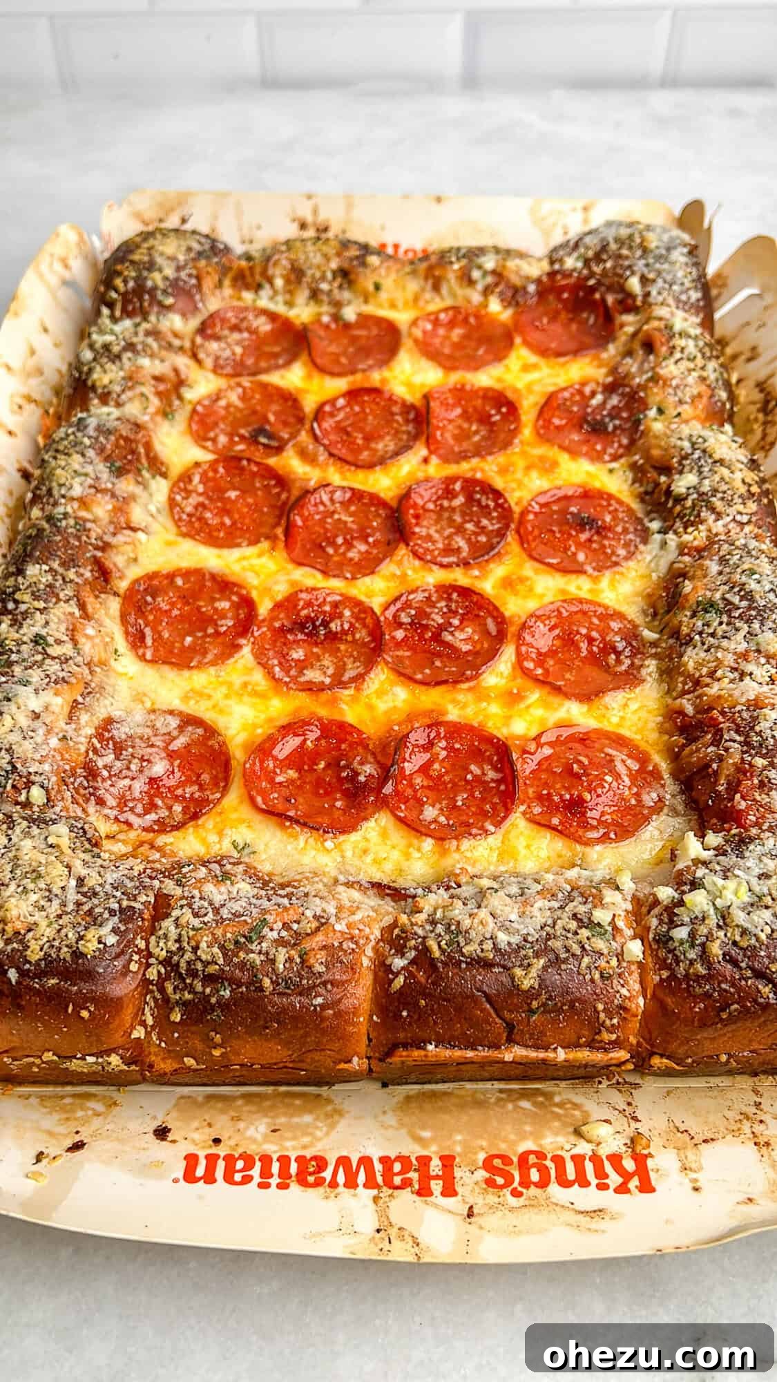 A whole Hawaiian roll pizza, hot out of the oven, before being sliced, showcasing its golden crust and bubbly toppings.