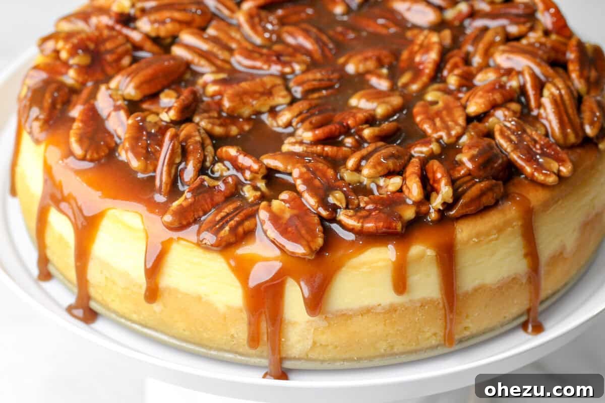 A stunning Bourbon Pecan Cheesecake on a stand, adorned with rich, dripping bourbon caramel sauce and toasted pecans.