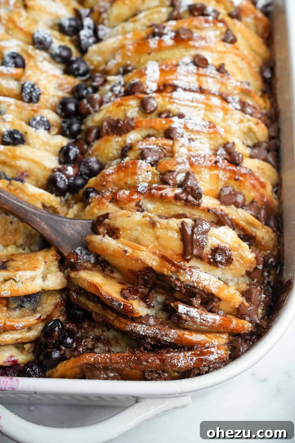 A heartwarming image of pancake casserole in a baking dish, with a spoon lifting out a generous serving, highlighting its golden-brown top and soft interior.