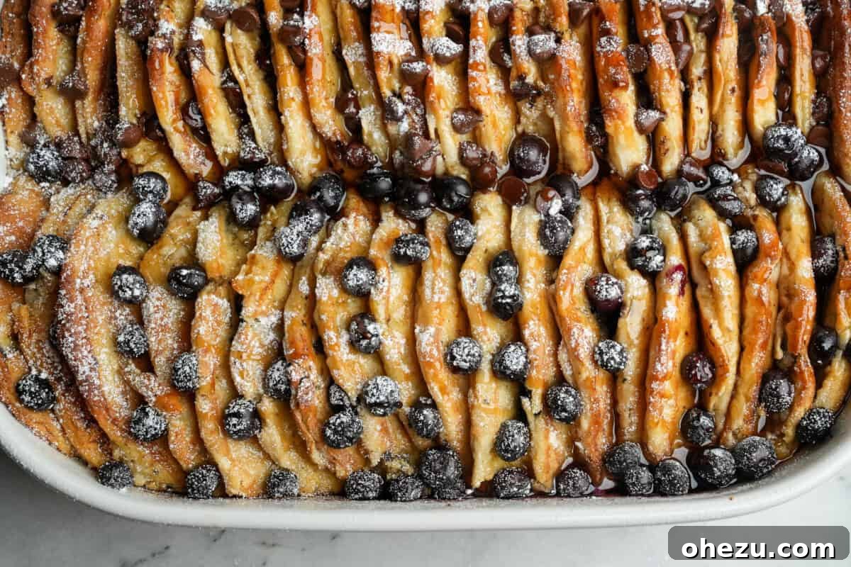 A close-up view of a pancake casserole featuring both blueberry and chocolate chip pancakes, neatly arranged side-by-side in a rectangular baking dish, ready for baking.