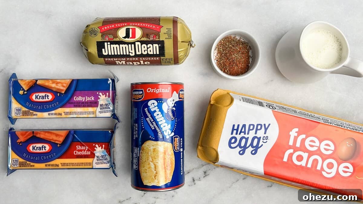 All the fresh ingredients laid out: a pack of biscuits, eggs, milk, shredded cheese, ground sausage, butter, flour, and a selection of seasonings.