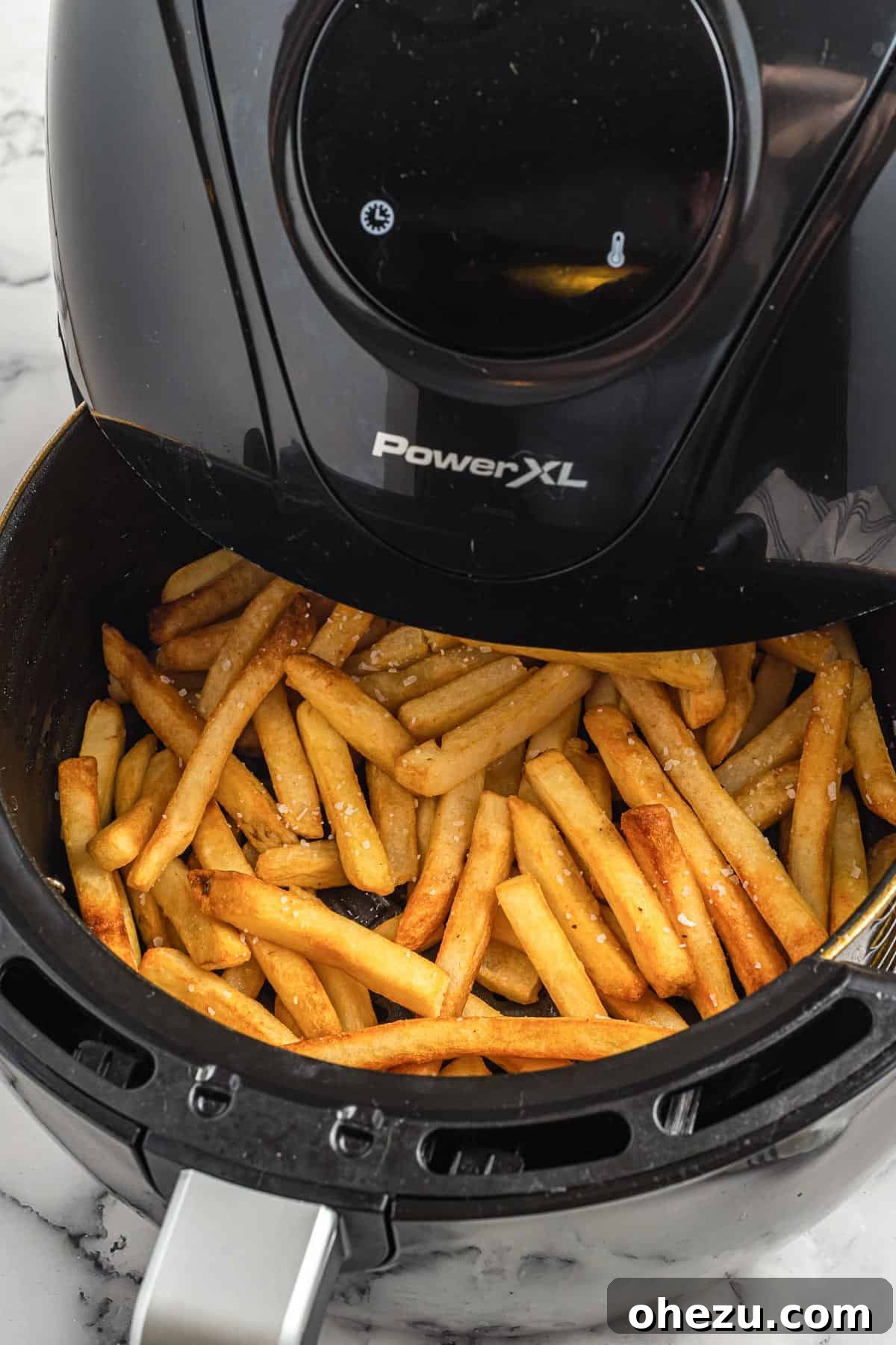 Golden Crispy Air Fryer Frozen French Fries 4 A close-up shot of perfectly golden-brown, crispy french fries freshly cooked and piled inside an air fryer basket.