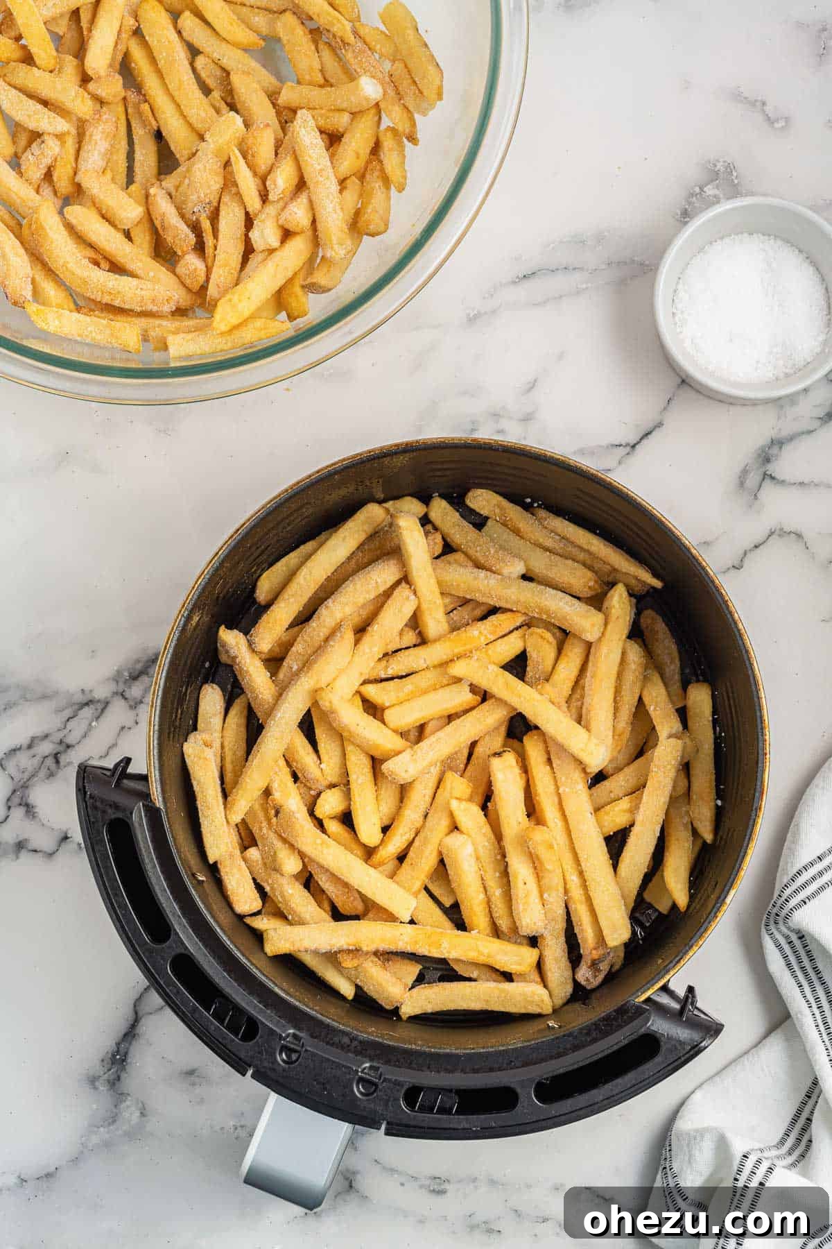 Golden Crispy Air Fryer Frozen French Fries 6 A heap of uncooked frozen french fries neatly arranged inside an air fryer basket, ready for the cooking process to begin.