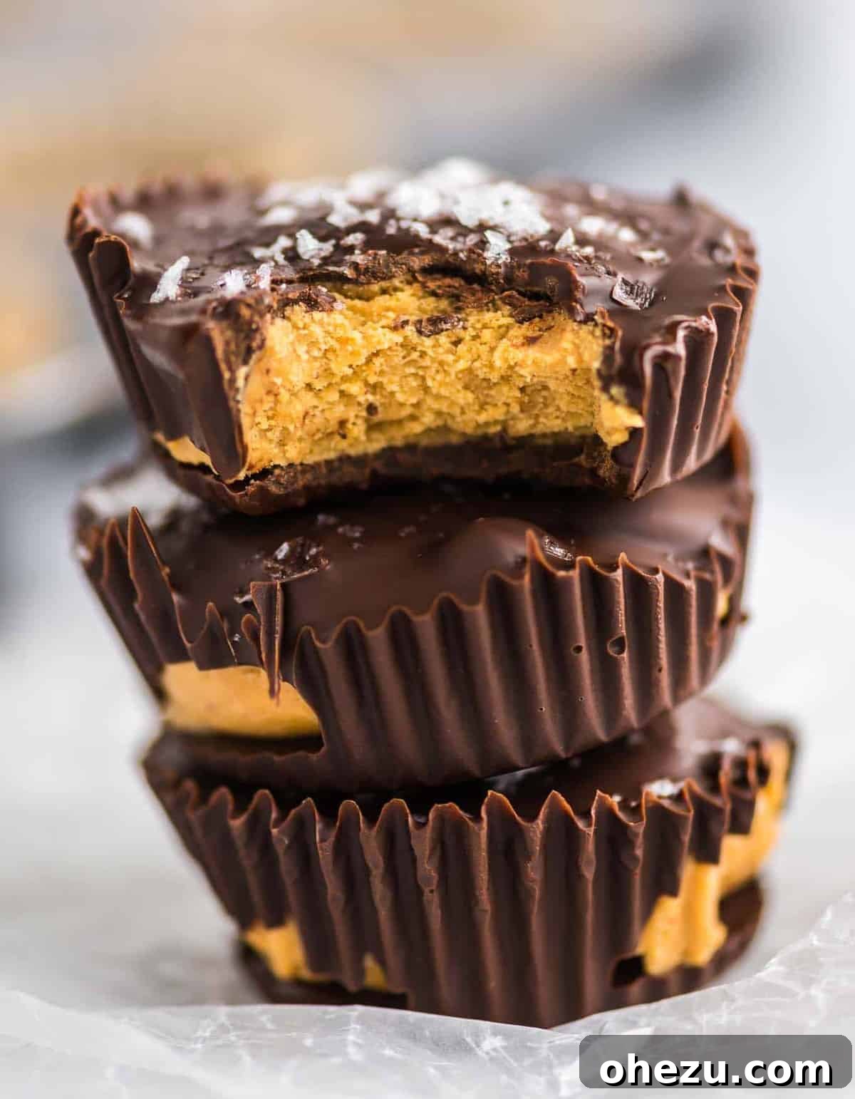 Three protein peanut butter cups stacked, with one bitten to show the creamy filling