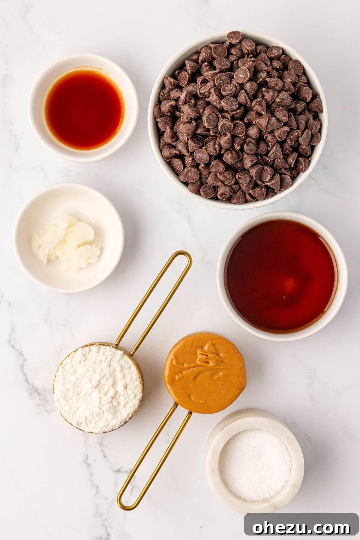 Ingredients laid out to make protein peanut butter cups, including chocolate chips, peanut butter, protein powder, and maple syrup.
