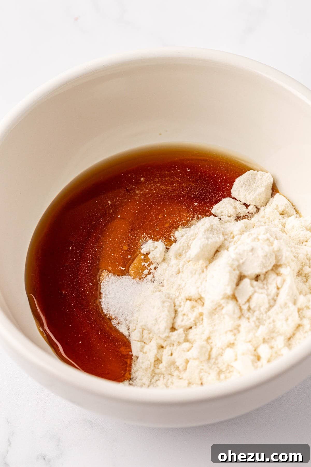 Protein powder and maple syrup being added to peanut butter