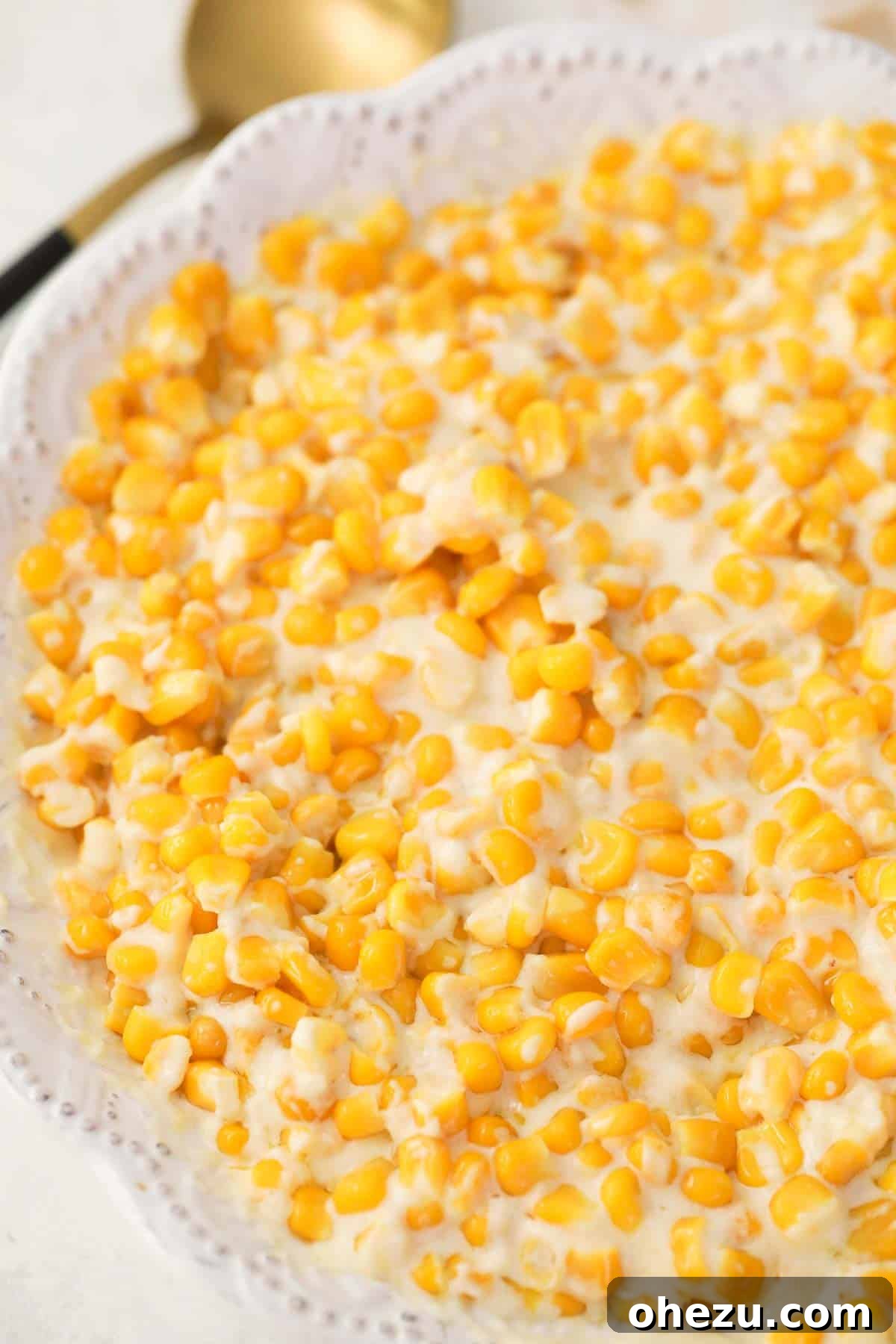 creamed corn with cream cheese in a white serving dish, garnished and ready to serve