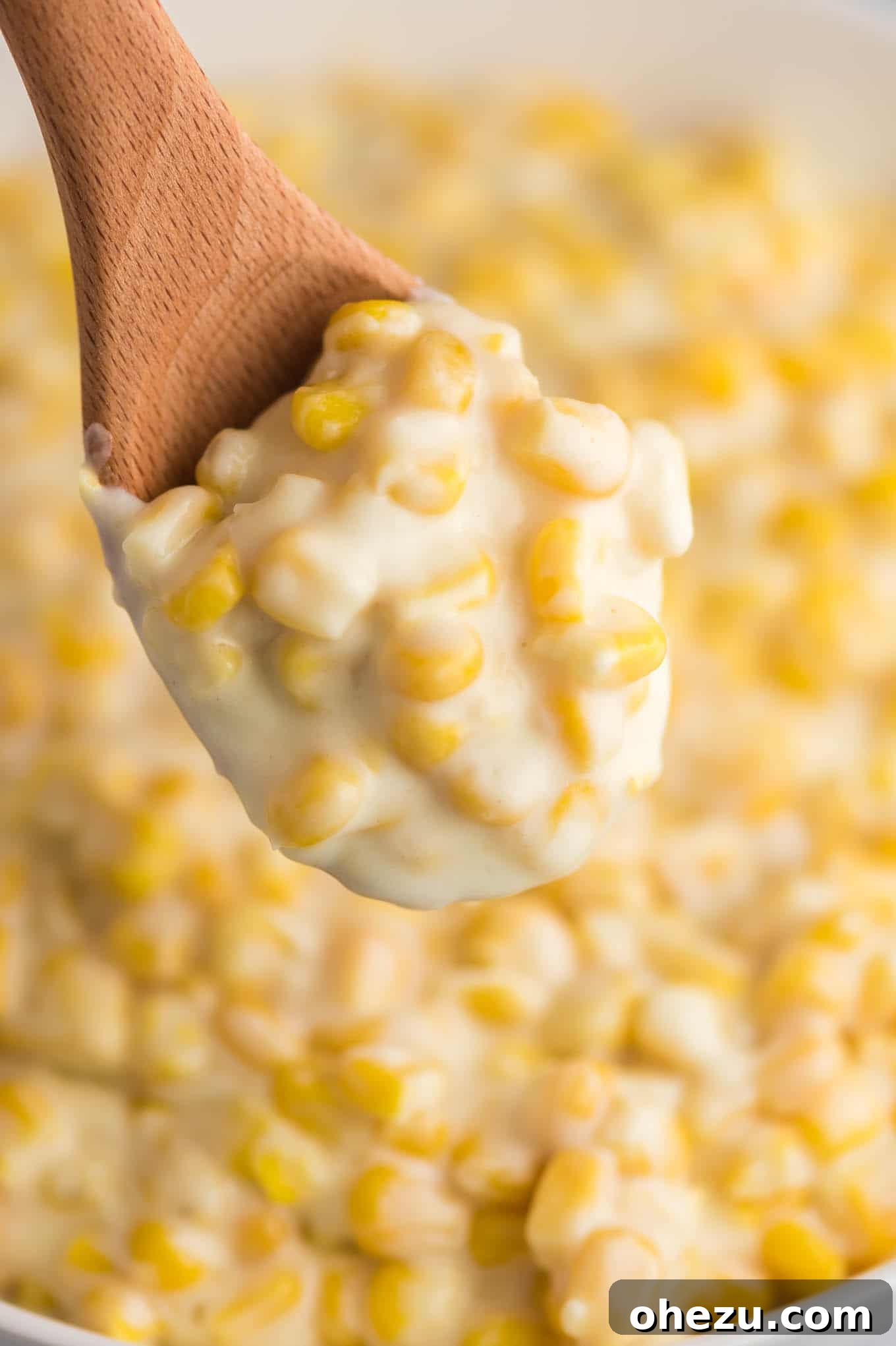 a wooden spoon taking a scoop of creamed corn from a large serving bowl, perfect for a family gathering
