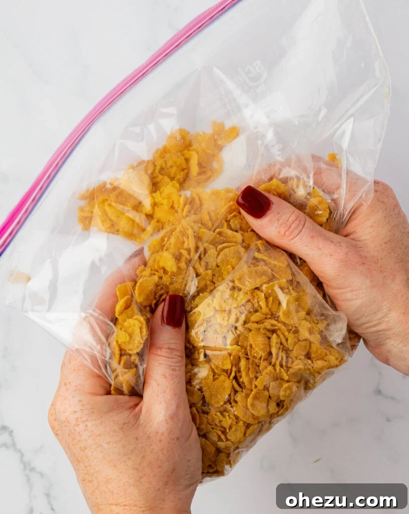 Hands crushing corn flakes inside a ziploc bag