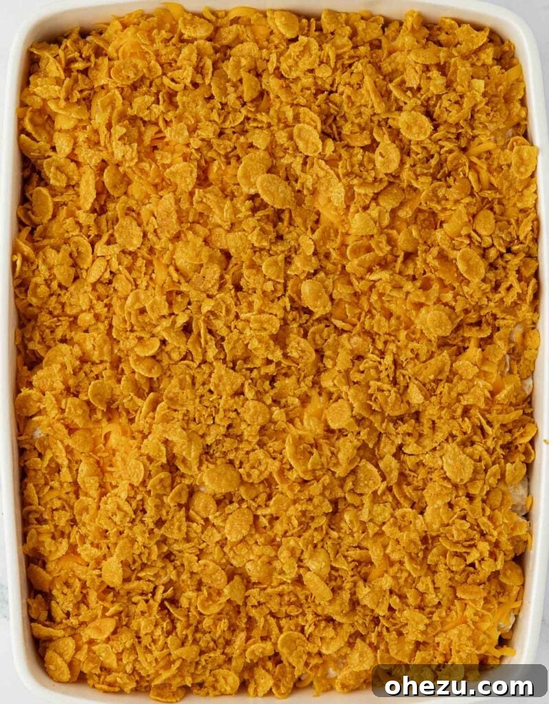 Cheesy potatoes in a baking dish with the buttery corn flake topping spread evenly on top