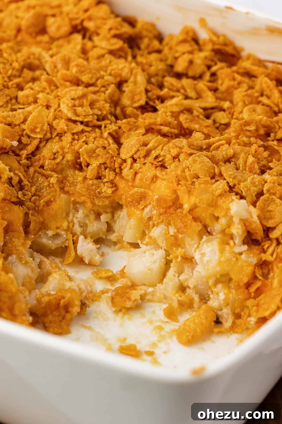 Wide shot of a full baking dish of cheesy potatoes with corn flakes, ready to be served