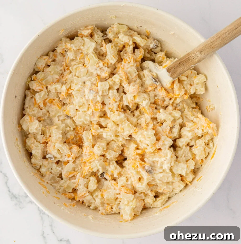 Mixing the cheesy potato casserole ingredients together in a bowl