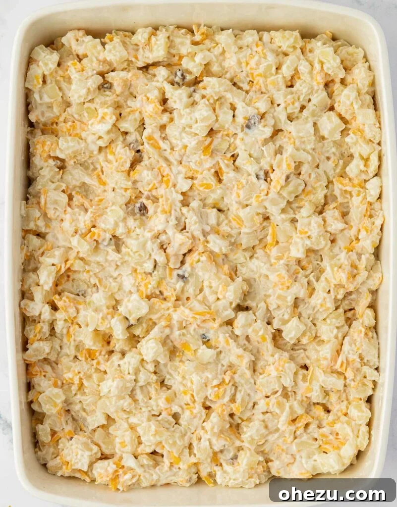 Creamy cheesy hash brown potatoes spread out in a baking dish