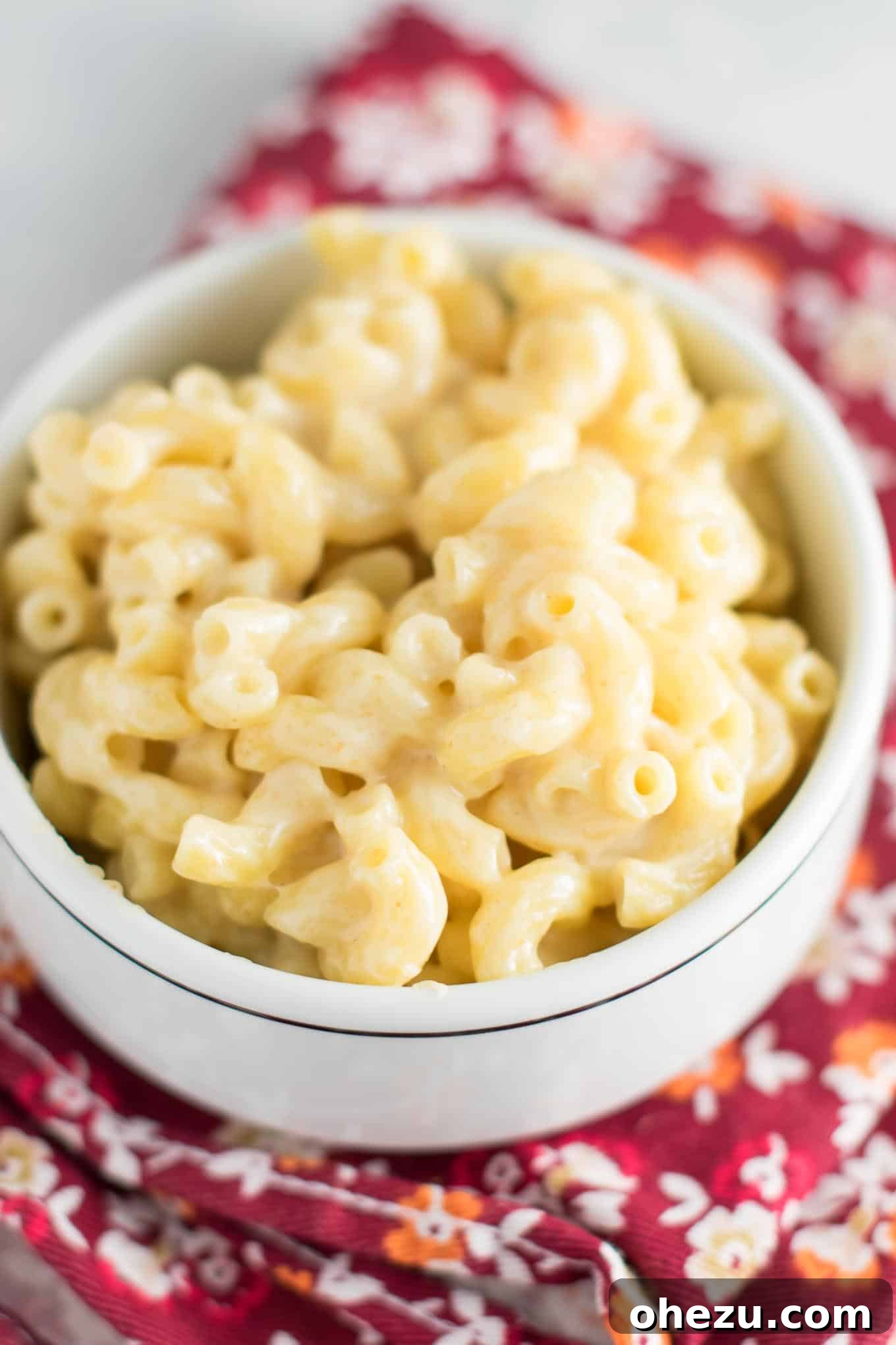 A large pot of creamy sharp cheddar mac and cheese with a spoon, ready for tasting