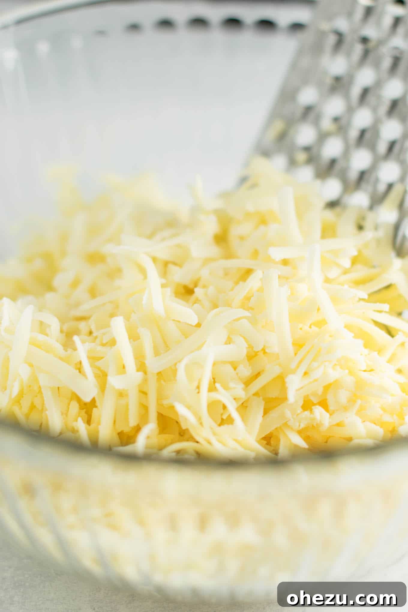 Close-up of freshly grated sharp cheddar cheese on a wooden cutting board, essential for the recipe