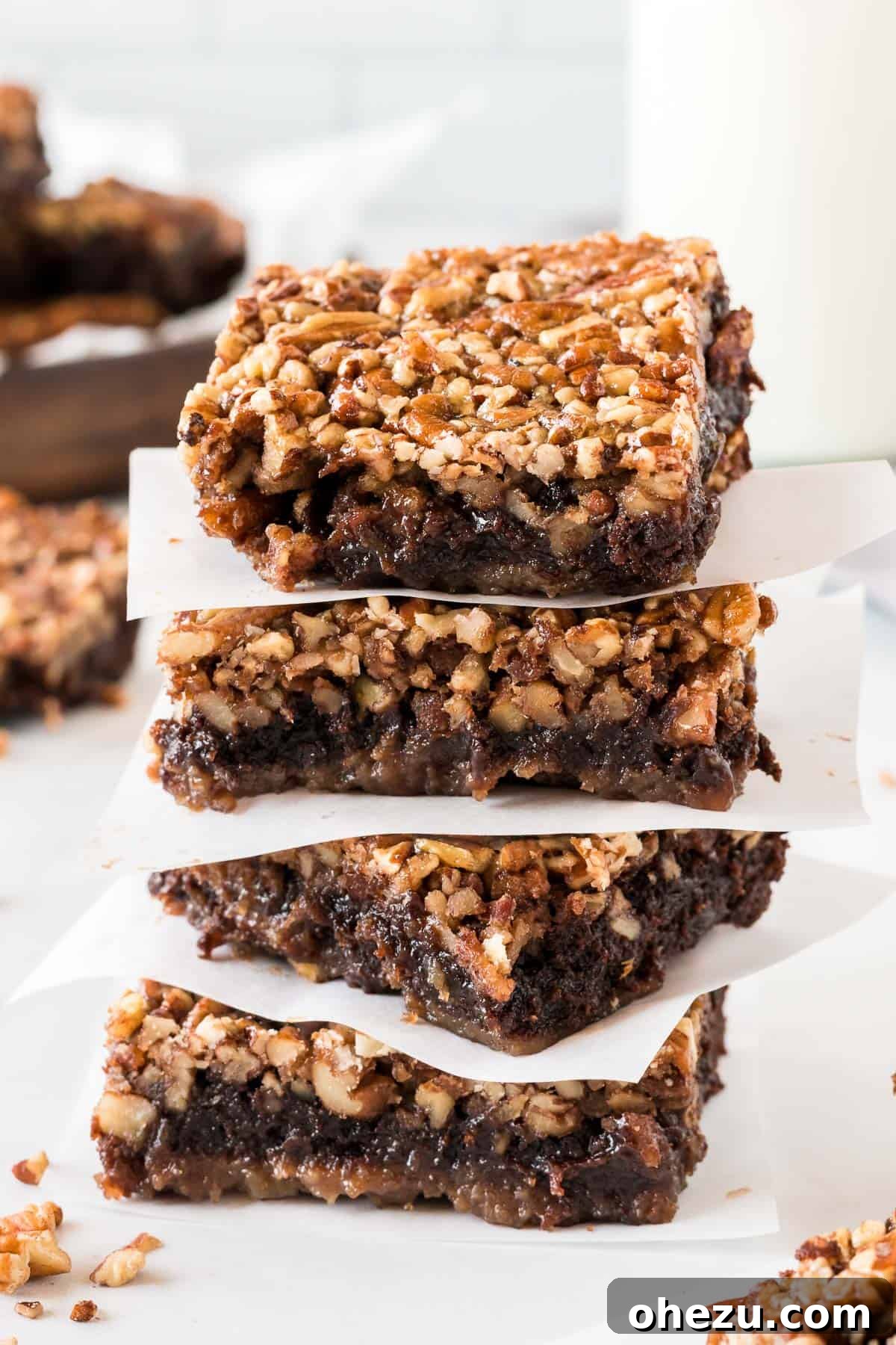 pecan pie brownies stacked between pieces of parchment paper