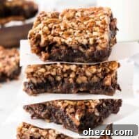 pecan pie brownies stacked between pieces of parchment paper