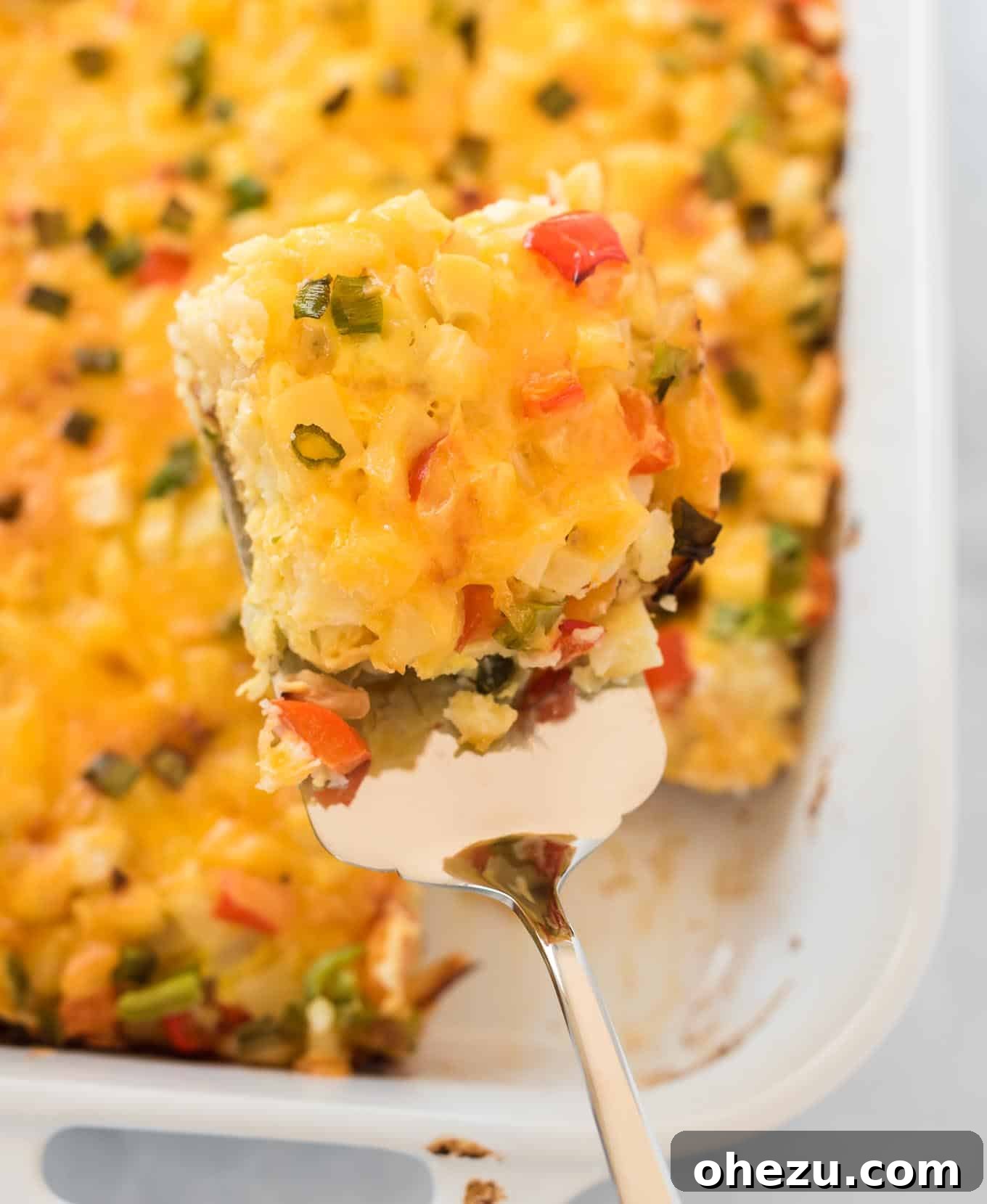 Sunrise Hash Brown Egg Bake 11 A spatula lifting a perfectly cut square of the cheesy hash brown egg casserole from the baking dish, showing its layered texture.