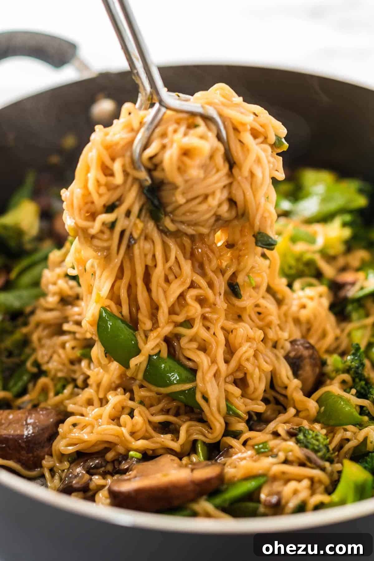 Sweet and Savory Teriyaki Noodles 7 Someone gracefully scooping a generous portion of freshly cooked Teriyaki Ramen Noodles from a skillet.