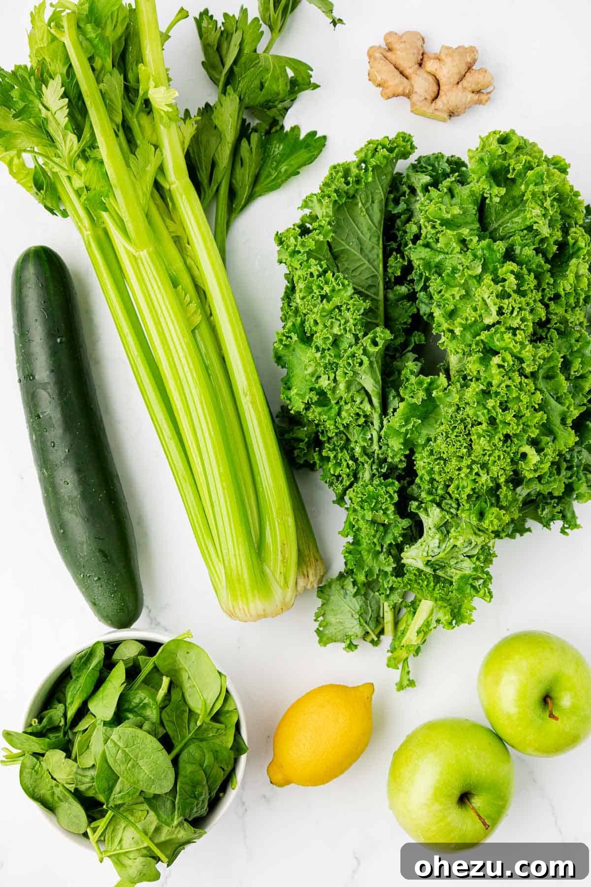 Vibrant Green Goodness 4 Fresh ingredients laid out on a counter, including kale, lemons, celery, cucumbers, spinach, green apples, and ginger, all ready for juicing.