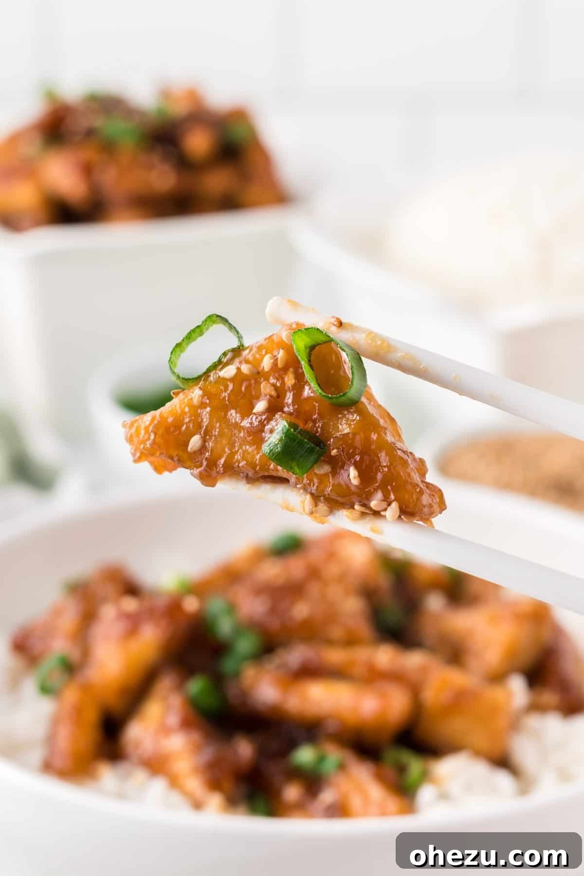chopsticks holding a piece of teriyaki tofu