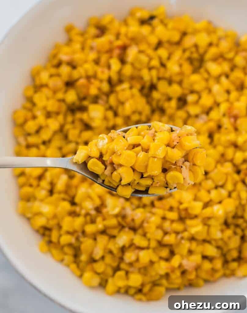 A spoon scooping perfectly roasted corn from a serving bowl, showcasing its golden color