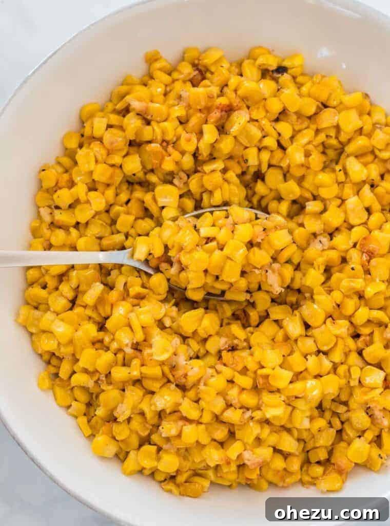 Another image of a spoon scooping roasted corn from a bowl, emphasizing texture