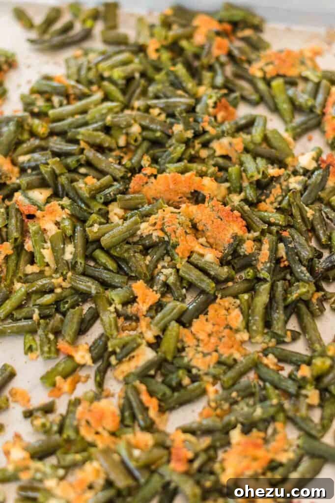 Roasted frozen green beans with crispy parmesan bits on a baking sheet