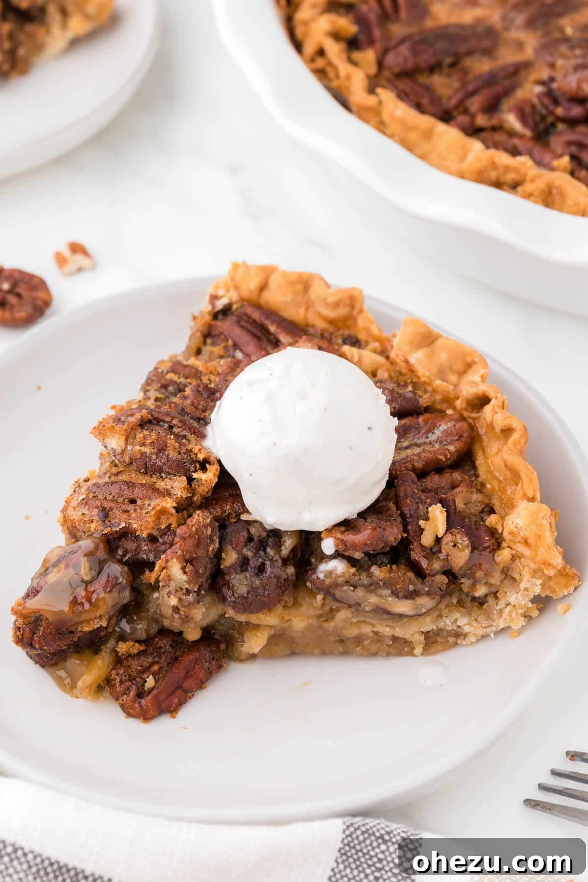 A beautiful slice of maple pecan pie topped with a generous scoop of creamy vanilla ice cream