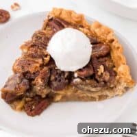A close-up of a slice of maple pecan pie topped with a scoop of vanilla ice cream
