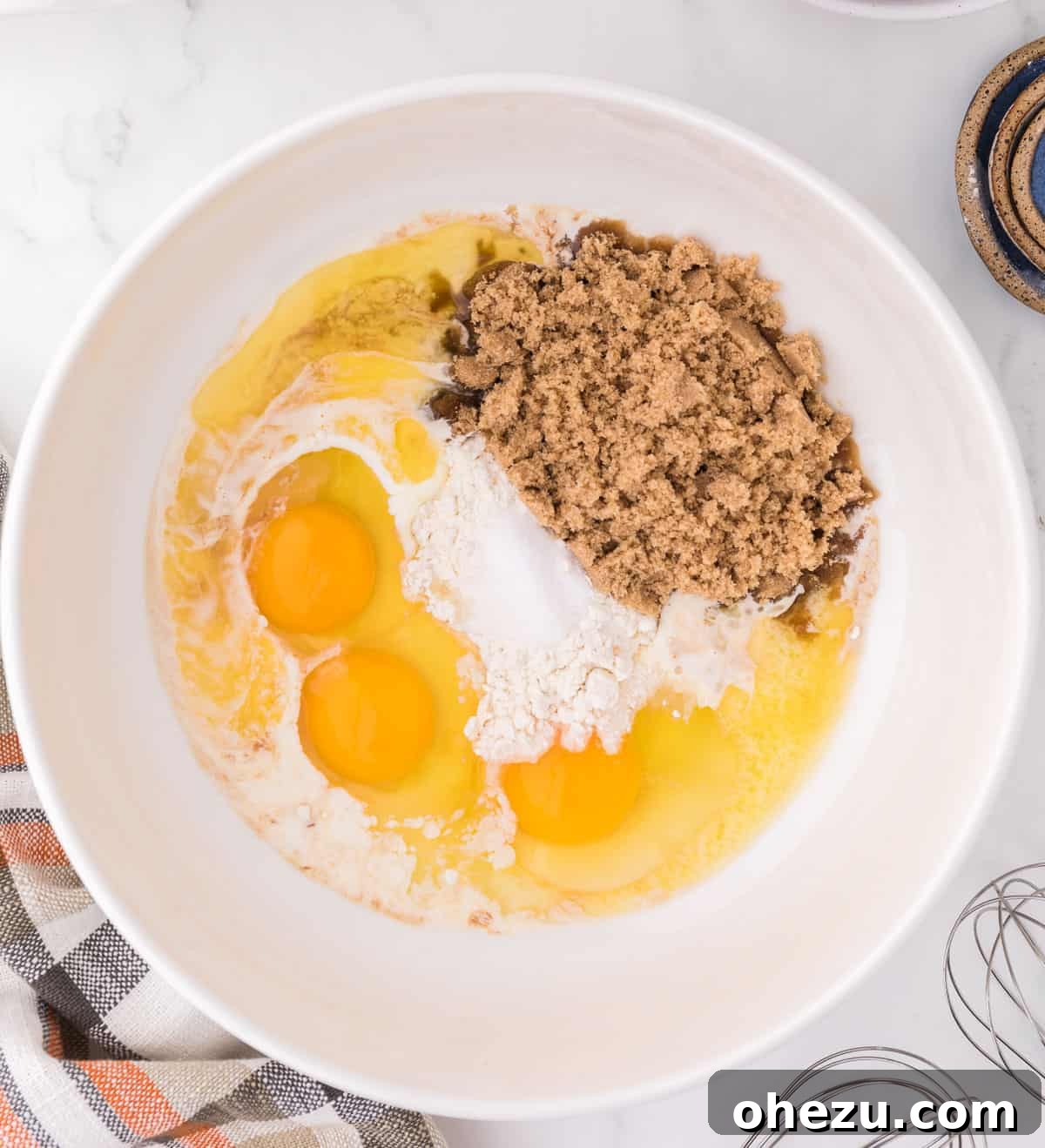A bowl containing brown sugar, eggs, and flour being mixed together for the pecan pie filling.