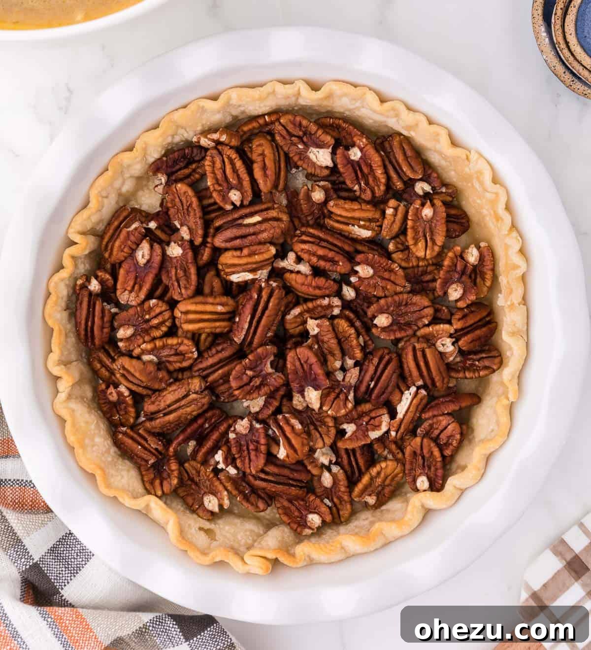 Whole pecan halves carefully arranged inside an unbaked pie crust.