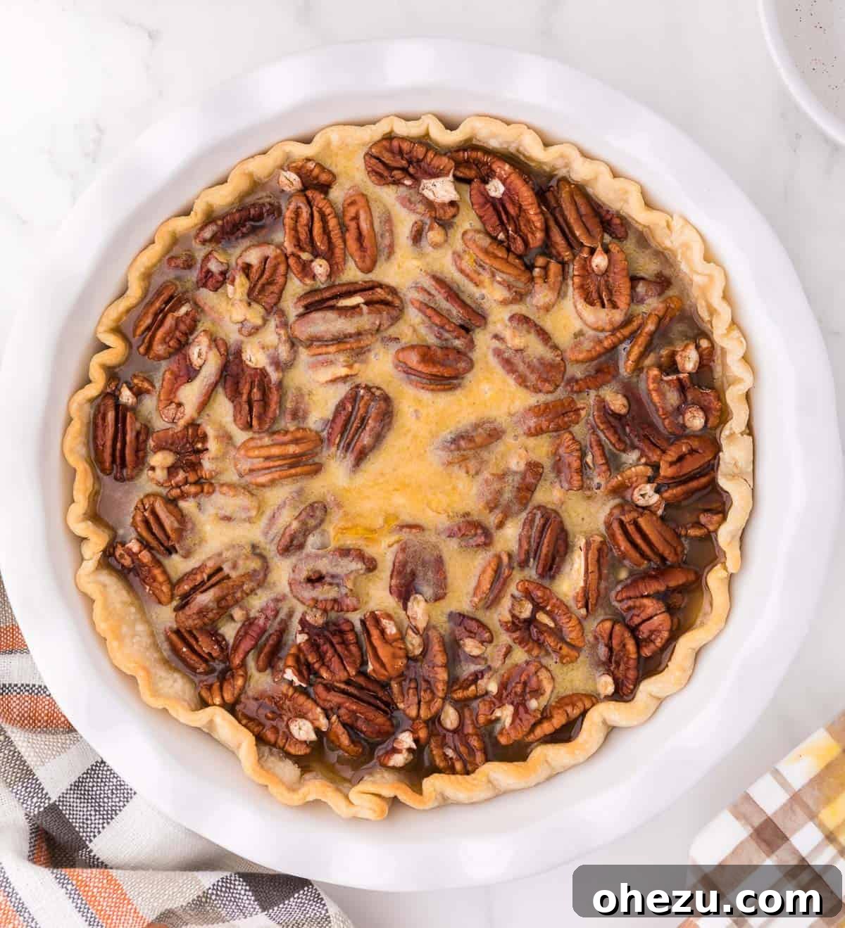 The liquid maple pecan filling being poured over the pecan halves in the pie crust.