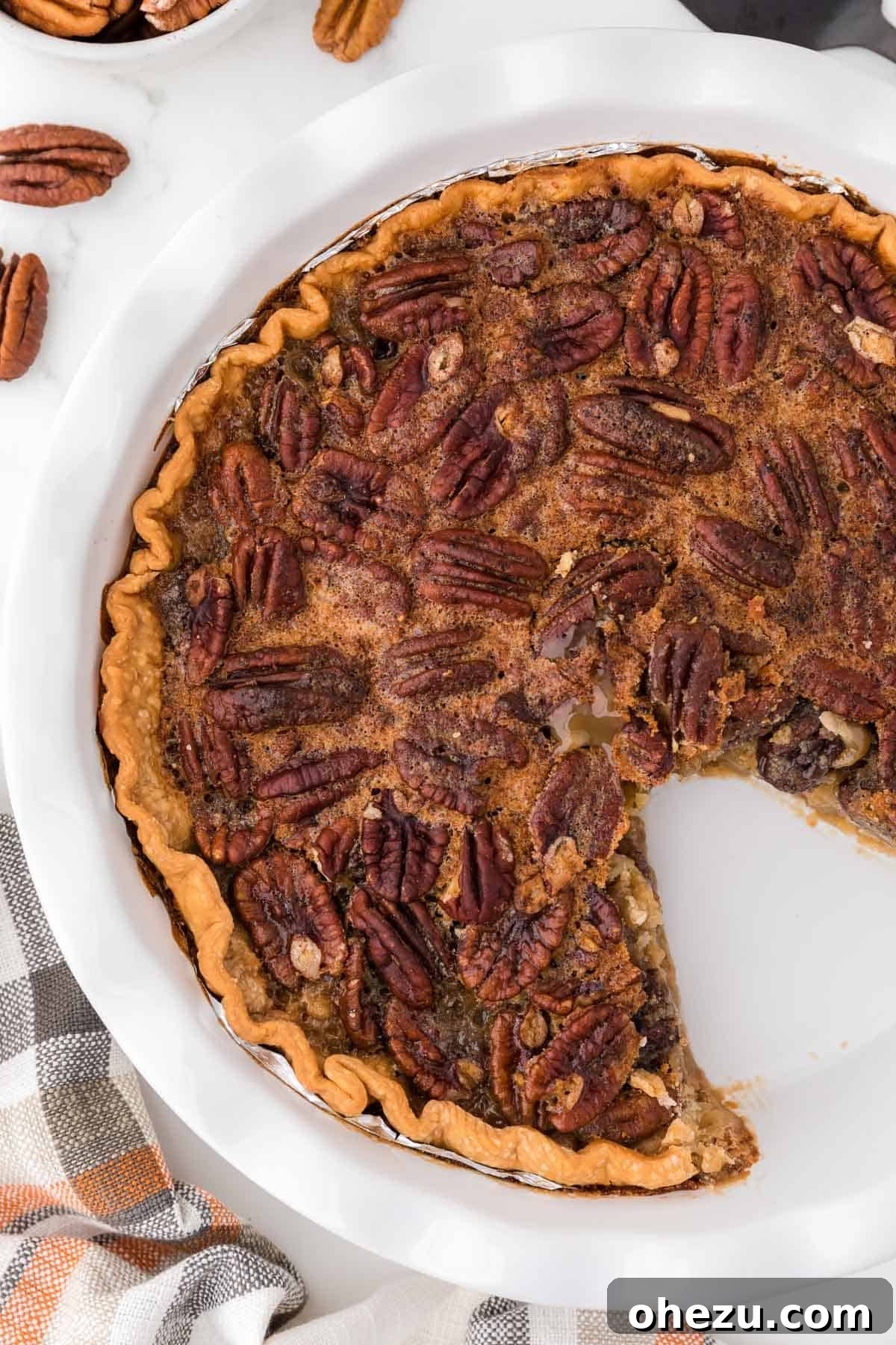 A freshly baked Maple Pecan Pie on a cooling rack with one slice already removed, showcasing its gooey center.