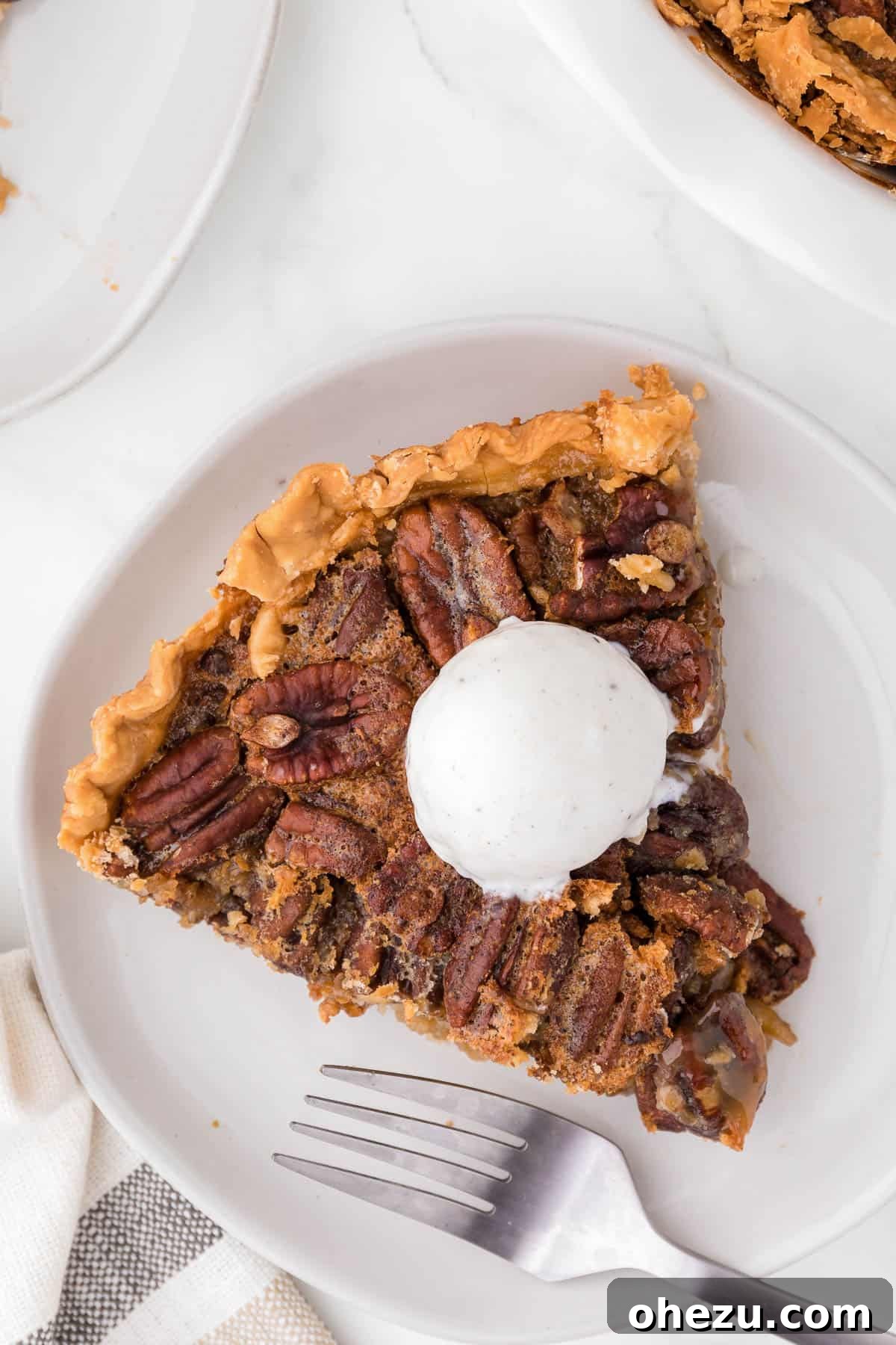 Another mouthwatering view of a slice of maple pecan pie, generously topped with a scoop of vanilla ice cream, ready to be eaten.