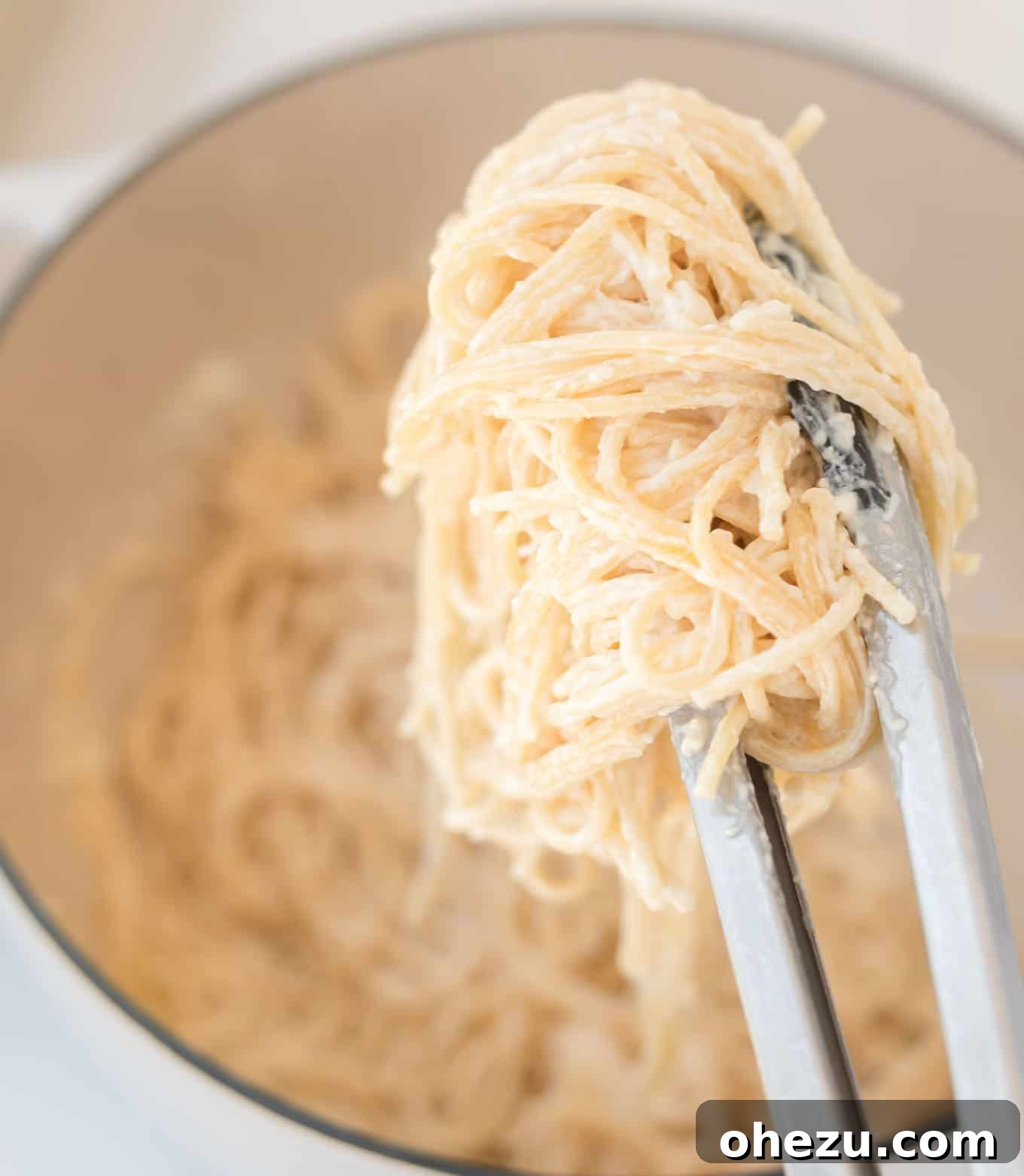 Large serving of cream cheese pasta with a spoonful being taken from the pot