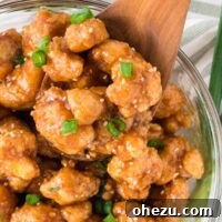 teriyaki cauliflower in a bowl topped with green onions and sesame seeds