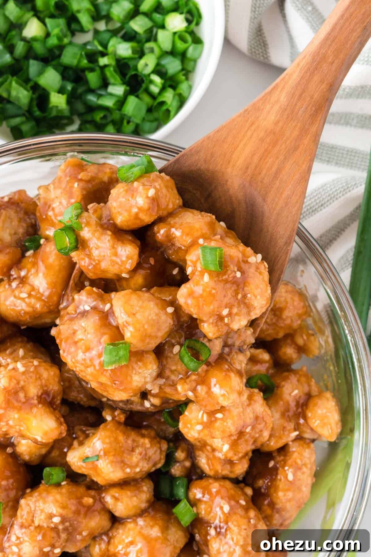 teriyaki cauliflower in a bowl topped with green onions and sesame seeds