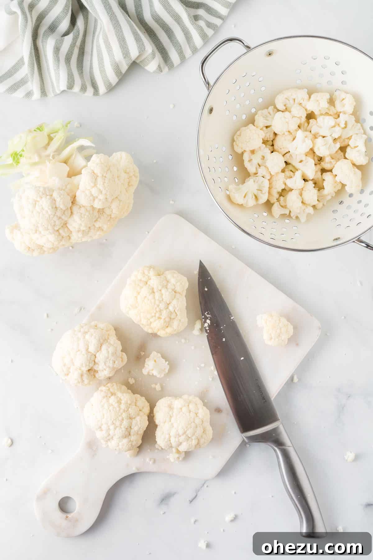 cutting board with cauliflower being cut with a knife