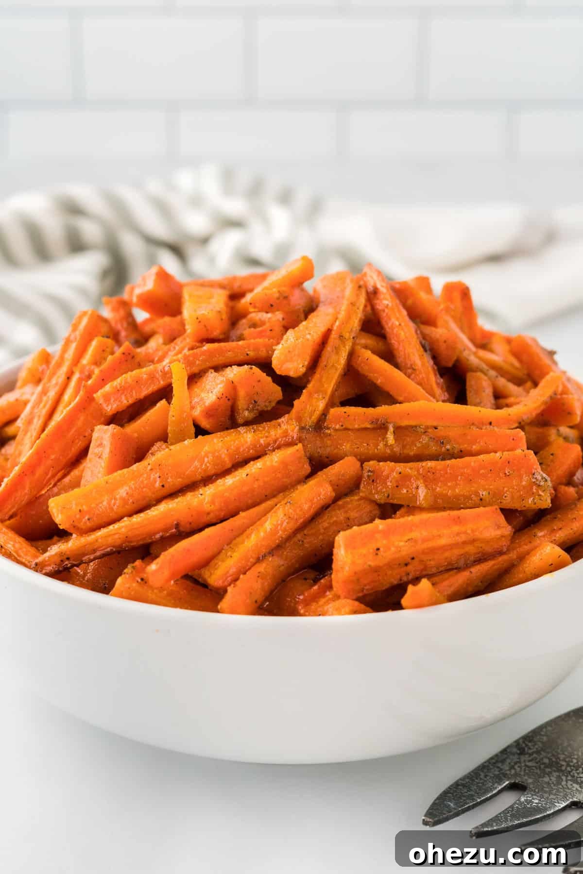 The Ultimate Roasted Carrots 10 A large, elegant white serving bowl brimming with a generous portion of freshly roasted carrots, ready to be enjoyed as a vibrant side dish.
