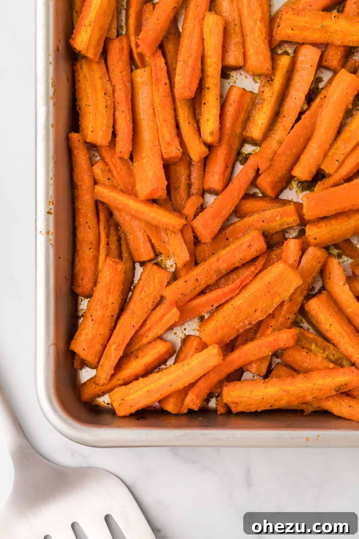 The Ultimate Roasted Carrots 9 Close-up photograph of impeccably roasted carrots with glorious golden-brown, caramelized edges, arranged on a baking sheet, glistening and fresh out of the oven.