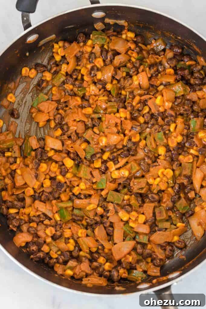 A vibrant, creamy black bean enchilada filling simmering in a skillet, showcasing the rich textures and colors before being rolled into tortillas.