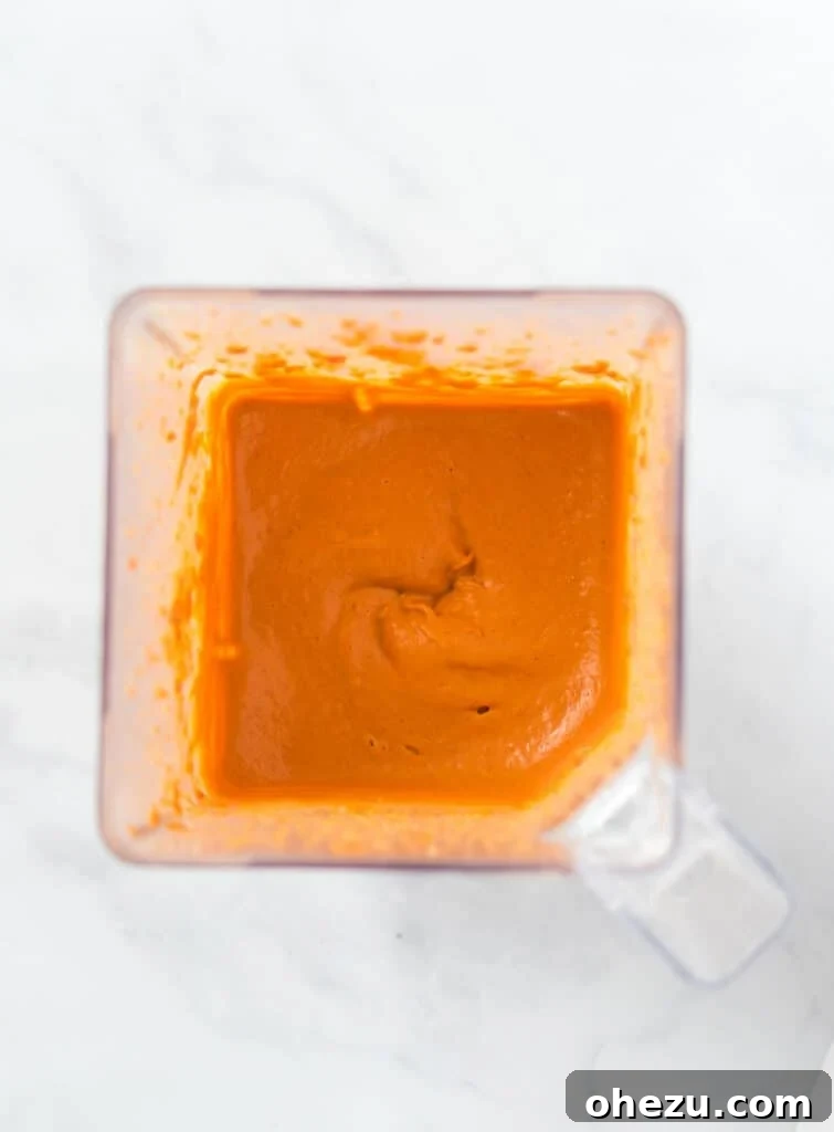 Smooth, creamy vegan cashew queso sauce being blended to perfection in a high-speed blender, ready to top the delicious enchiladas.